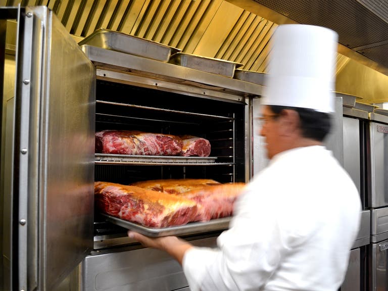 A chef loads prime rib into an oven at Lawry's The Prime Rib