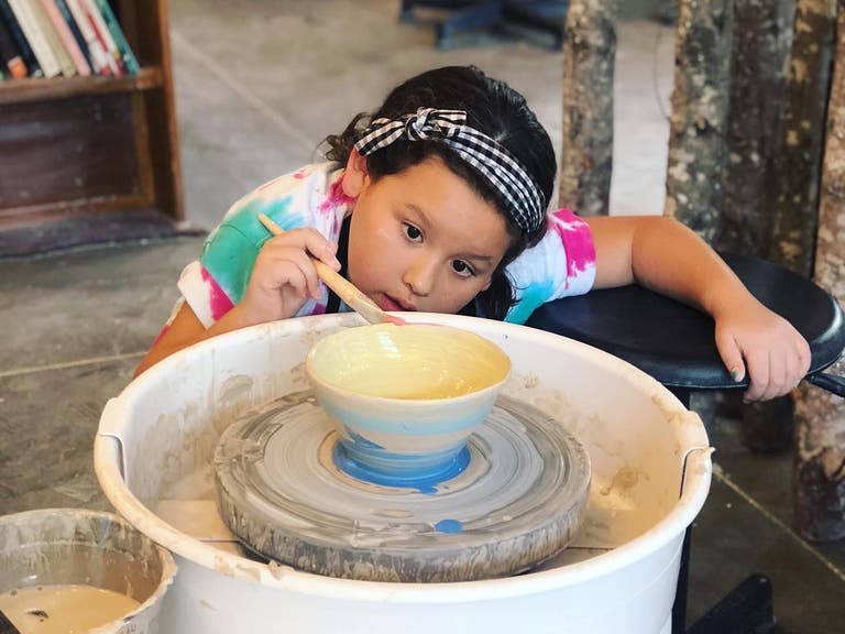 A young girl paints her bowl at Bitter Root Pottery