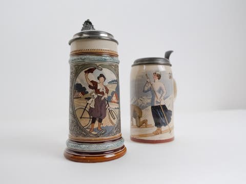 Villeroy and Boch. Girl Holding Safety Bicycle. Stein, etched, inlay. 1900. Collection of the American Museum of Ceramic Art; gift of Bob and Colette Wilson. (foreground)  Villeroy and Boch. Woman Skiing. Stein, print-under-glaze. 1911. Collection of the American Museum of Ceramic Art; gift of Bob and Colette Wilson. (background)