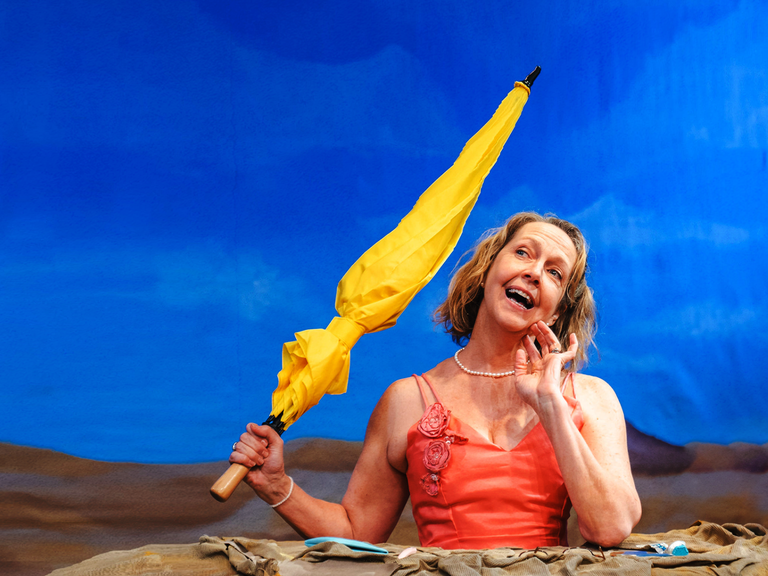 A woman in a mound smiles and holds a yellow umbrella.