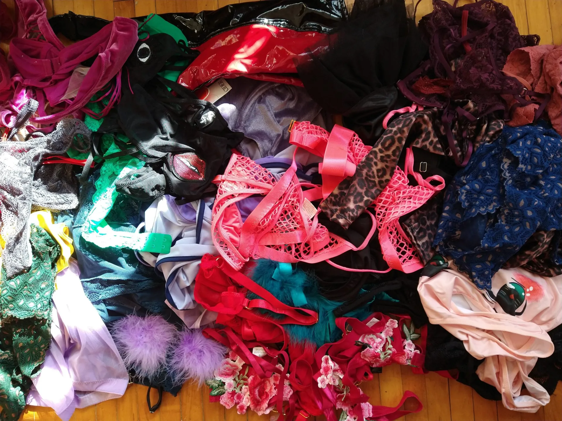 Pile of lacy and patterned lingerie on a wooden floor.  