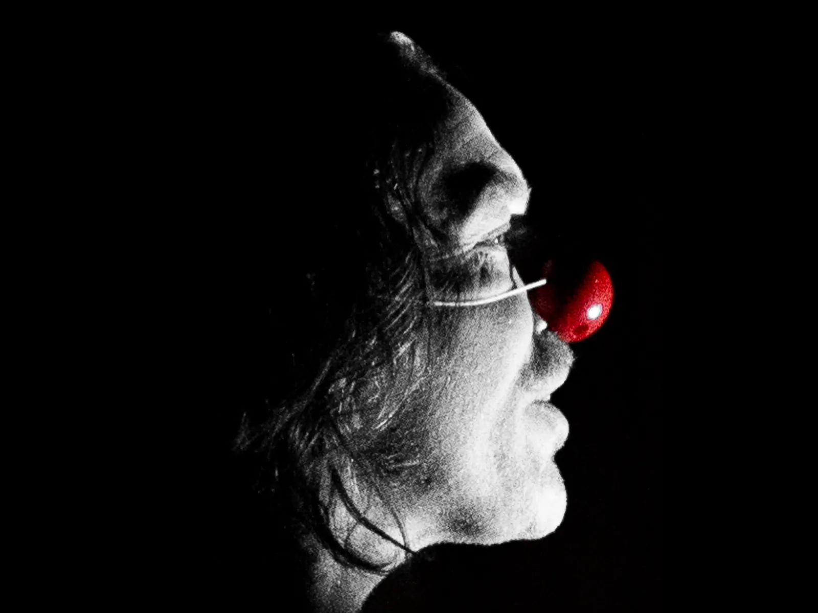black and white profile of mans wearing a clown nose