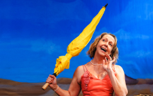 A woman in a mound smiles and holds a yellow umbrella.