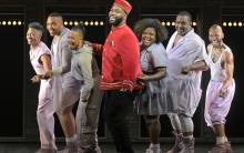A Strange Loop cast, with the lead character of Usher in the center and the ensemble cast of his "thoughts" surrounding him as they sing a musical number together.