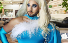Drag queen Butter McGhee stands with hands on hips in an electric blue dress, long blonde-white hair, in Gracias Madre's main room.